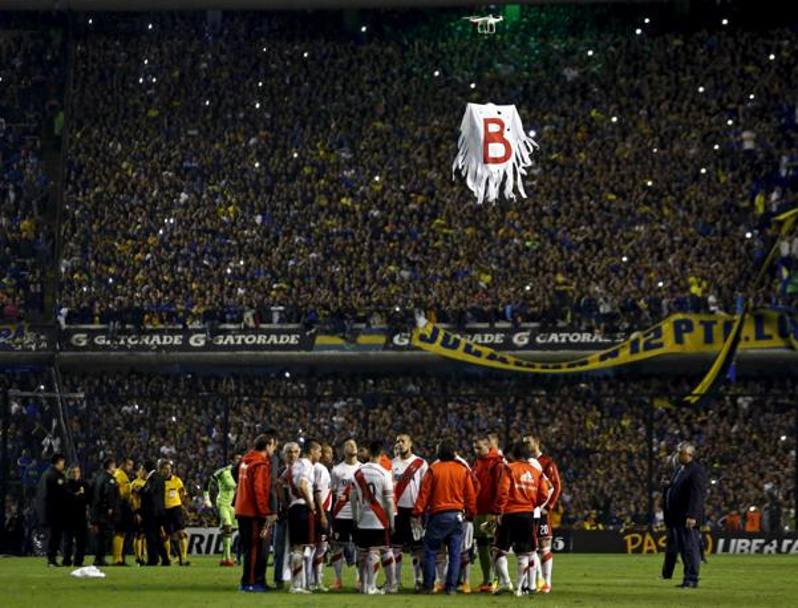 I giocatori del River Plate riuniti a centrocampo, sopra di loro un drone comandato dai tifosi del Boca (un altro motivo che da solo avrebbe potuto portare alla sospensione del match) su cui campeggia uno stendardo con una grande B, a ricordare agli odiati rivali l&#39;onta della retrocessione del 2011. Reuters